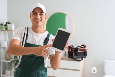 Tuvalette boş tablet bilgisayarı olan erkek tesisatçı.