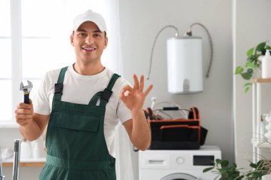 İngiliz anahtarı olan erkek tesisatçı banyoda iyi görünüyor.