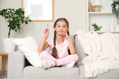 Evdeki kanepede fikri olan tatlı küçük kız.