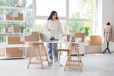 Online mağaza deposunda çalışan defteri ve paketleri olan hamile bir satıcı.