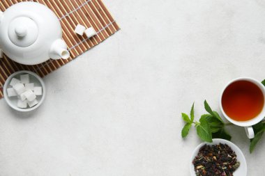 Çay demliği, çay fincanı ve arka planda yeşil yapraklarla güzel bir kompozisyon.