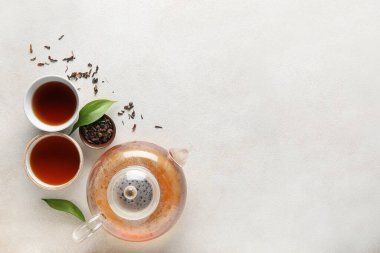 Çay demliği, çay fincanı ve hafif grunge arka planda yeşil yapraklı güzel kompozisyon.