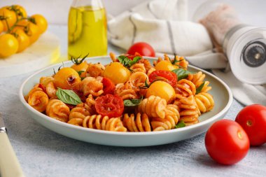 Domatesli lezzetli fusilli makarna ve hafif grunge arka planda fesleğen.