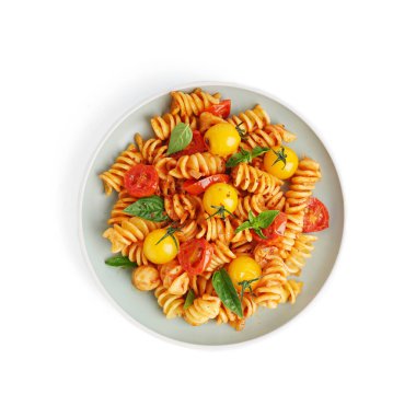 Beyaz arka planda domatesli ve fesleğenli lezzetli fusilli makarna.