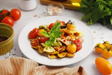 Masada domates ve fesleğenli bir tabak lezzetli farfalle makarna.