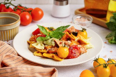 Masada domates ve fesleğenli bir tabak lezzetli farfalle makarna.