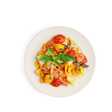 Beyaz arka planda domates ve fesleğenli bir tabak lezzetli farfalle makarna.