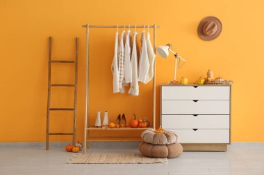 Sonbahar kıyafetleri, çekmeceler ve balkabaklarıyla dolu bir oda.