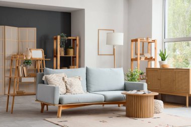 Gri kanepesi, raf ünitesi ve sehpası olan modern oturma odasının içinde.