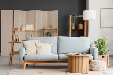 Gri kanepesi, raf ünitesi ve sehpası olan modern oturma odasının içinde.