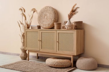 Değişik ev dekorları ve bej duvarın yanında kuru kamış vazoları olan şık bir tuvalet.