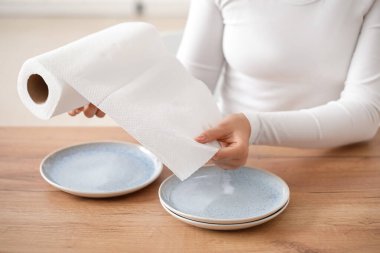 Mutfakta temiz tabakları ve rulo kağıt havluları olan güzel genç bir kadın.