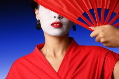 Karanlık arka planda yelpazesi olan güzel bir geyşa.