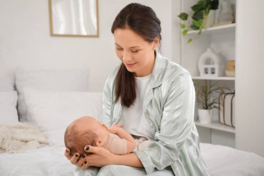 Mutlu anne, tatlı, uyuyan bebeğiyle evde oturuyor.