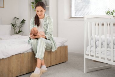 Mutlu anne, tatlı, uyuyan bebeğiyle evde oturuyor.