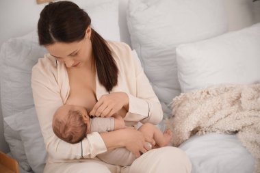 Anne, tatlı, uyuyan bebeğini evde emziriyor.