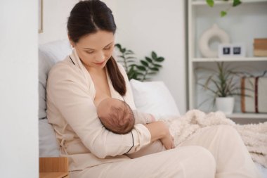 Mutlu anne, tatlı, uyuyan bebeğini evde emziriyor.