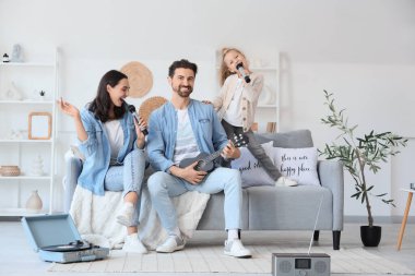 Evde mikrofonlu ve ukuleleli mutlu bir aile karaoke yapıyor.