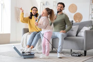 Evde mikrofonlu ve pikaplı mutlu bir aile karaoke yapıyor.