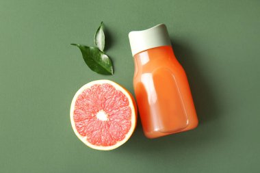 Bir şişe lezzetli greyfurt suyu ve yeşil arka planda taze meyve.