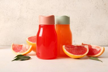 Lezzetli greyfurt suyu şişeleri ve hafif arka planda taze meyveler içeren kompozisyon