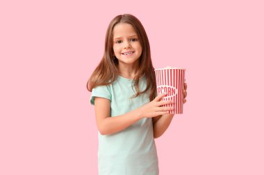 Pembe arka planda patlamış mısırı olan mutlu küçük kız