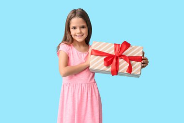 Mavi arka planda hediye kutusu olan mutlu küçük kız.