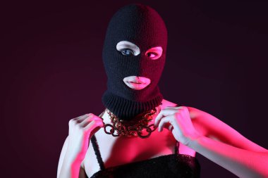 Siyah kar maskeli güzel bir kadın ve siyah arka planda şık bir zincir kolye.