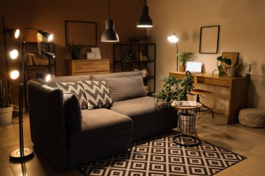 Gri kanepesi, çiçekleri ve gece lambasıyla modern tarz oturma odası.