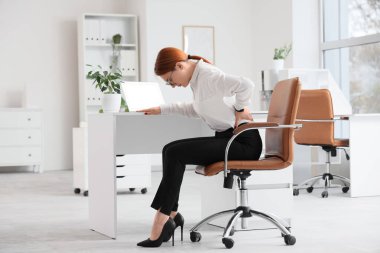 Güzel genç iş kadını koltukta sırt ağrısı çekiyor.