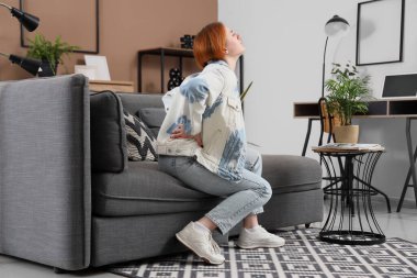 Evdeki kanepede sırt ağrısı çeken güzel bir genç kadın.