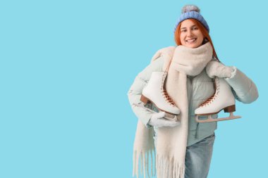 Mavi arka planda buz pateni yapan güzel, genç bir kadın.