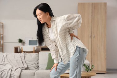 Evinde sırt ağrısı çeken güzel bir Asyalı kadın.