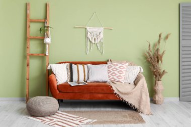 Yastıklı rahat kanepe, merdiven ve vazonun içindeki vazoda otlar.