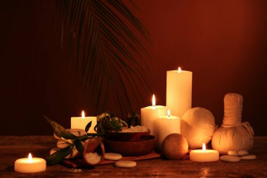 Koyu ahşap masa üzerinde yanan mumlar ve bambu saplı güzel bir spa kompozisyonu.