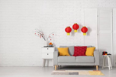 Çin Yeni Yılı için dekore edilmiş oturma odasının içi kanepe, masa ve katlanır ekran ile süslenmiş.