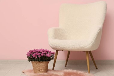 Kasımpatı çiçekli hasır sepet halının üzerinde ve pembe arka planda koltuk