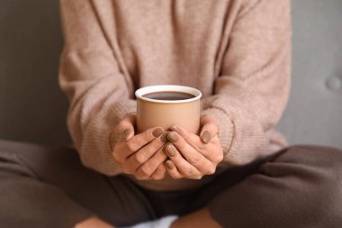 Evdeki kanepede oturan bir fincan sıcak çikolatalı güzel genç kadın.