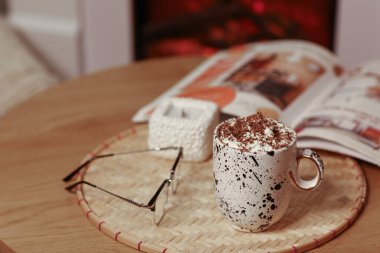 Krem şantili, gözlüklü ve kitaplı bir fincan sıcak çikolata.
