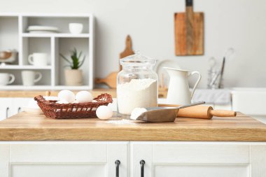 Mutfak tezgahında hamuru hazırlamak için merdane, kepçe ve yumurta ile kavanozda un.