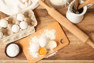 Yumurta, un, bir kase tuz ve ahşap zemin üzerinde hamur hazırlamak için kap.