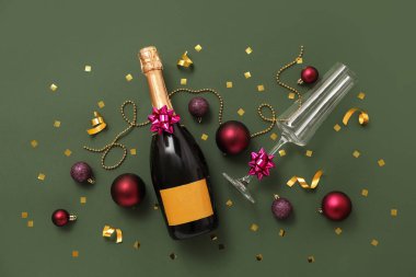 Cam kaplı bir şişe şampanya, yeşil arka planda noel topları ve boncuklar.