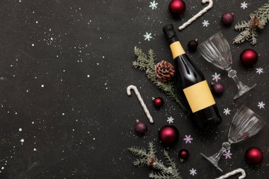 Gözlüklü bir şişe şampanya, Noel baloları ve siyah grunge arka planda dekor.