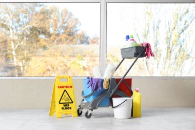 Oda penceresinin yanında temizlik malzemesi olan bir araba.