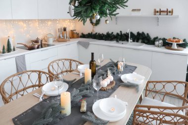 Modern mutfak, şenlikli masa dekorasyonu, parıldayan ışıklar ve Noel süslemeleri.