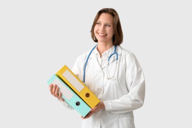 Beyaz arka planda klasörleri olan güzel bir kadın doktor.