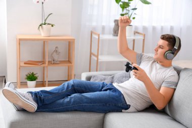 Kulaklıklı genç çocuk evde video oyunları oynuyor.
