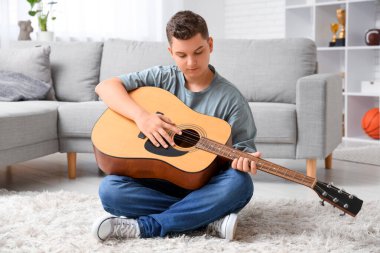 Evde gitar çalan genç çocuk