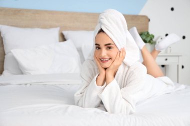 Duştan sonra havluyla bornozlu genç bir kadın evde yatıyordu.