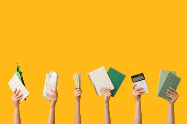 Sarı arka planda farklı kırtasiye malzemesi olan kadın elleri